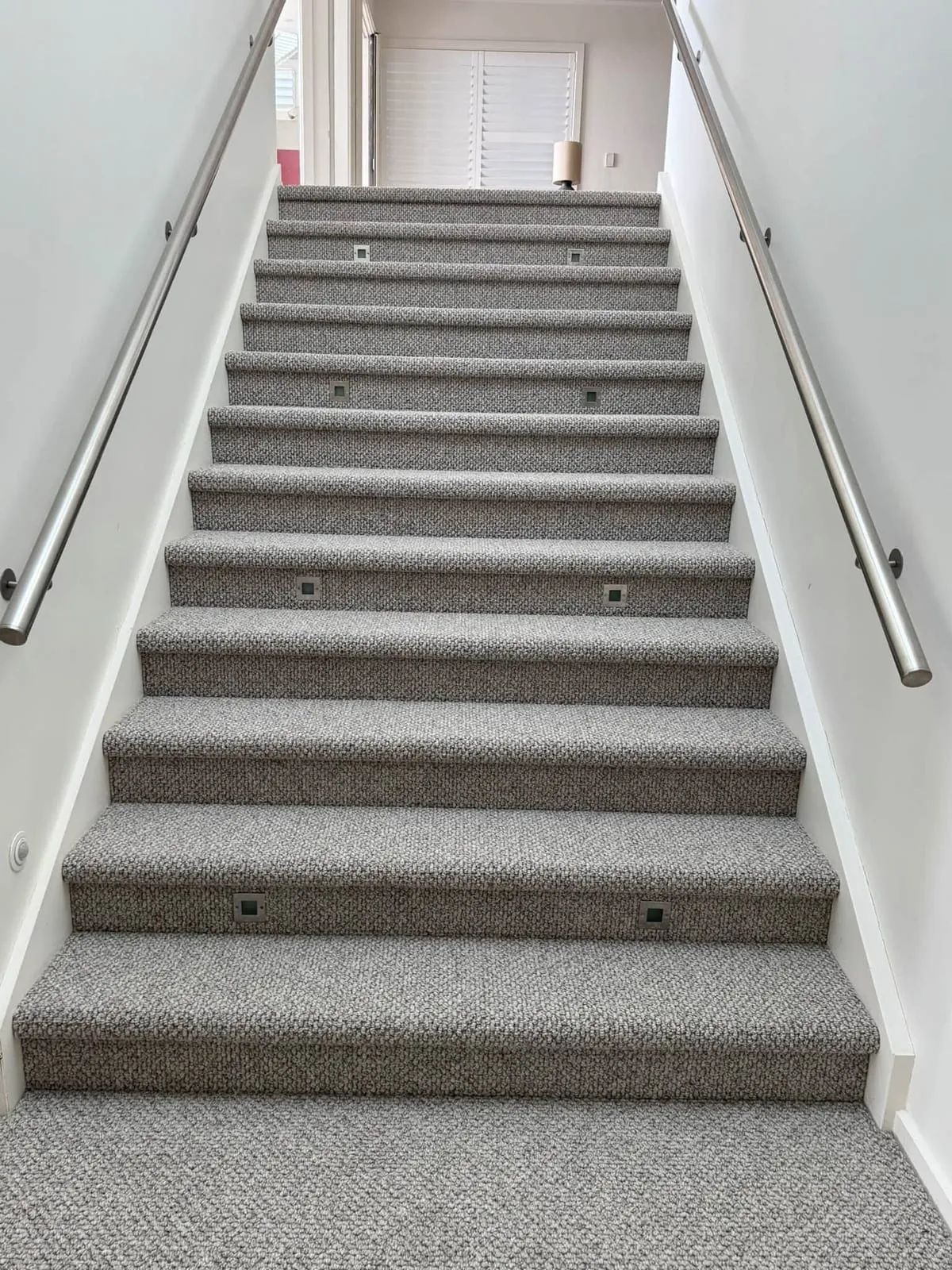 Carpeted staircase with a stainless handrail