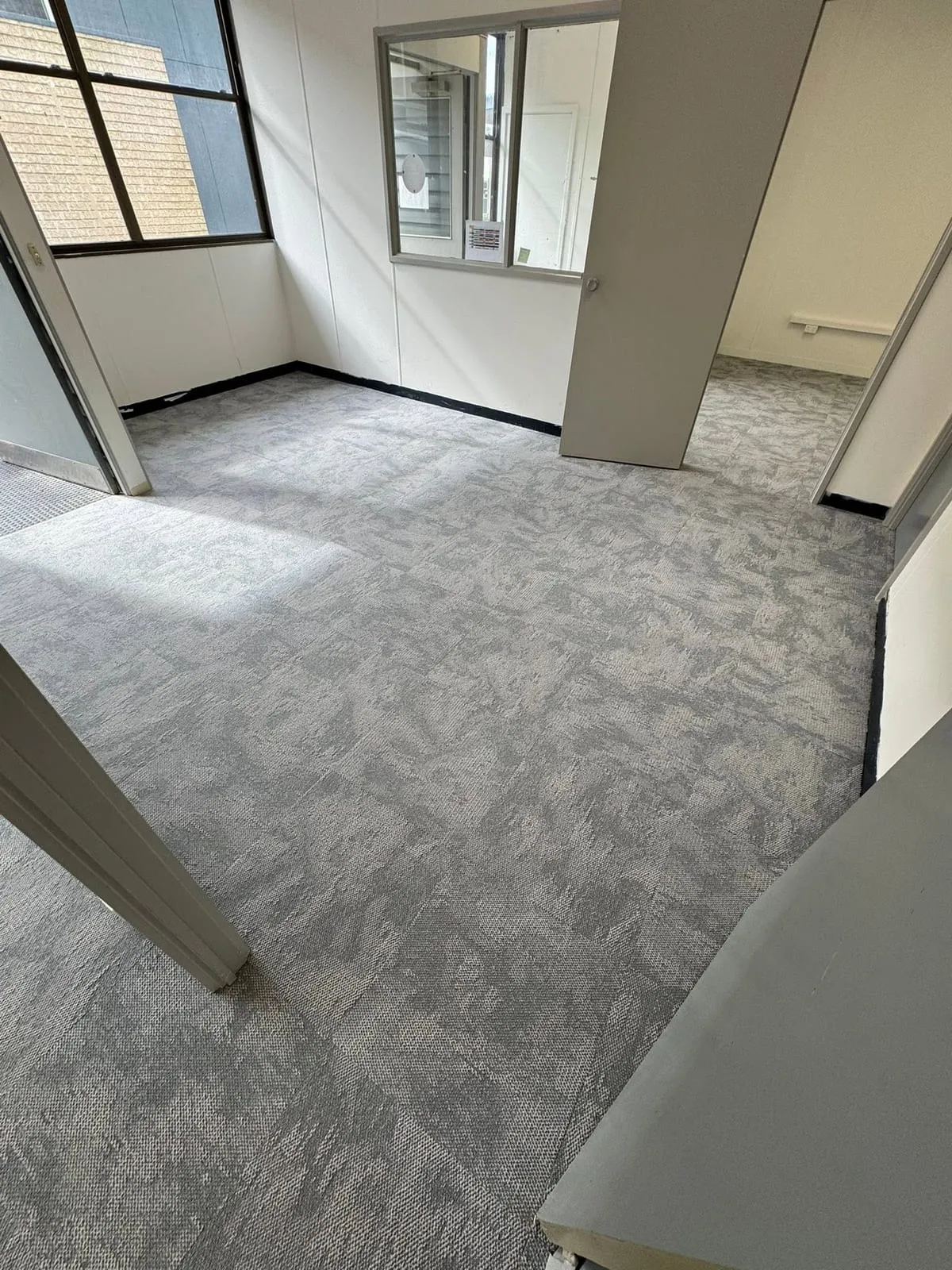 Grey carpet tiles laid through a bright room, Crib Point