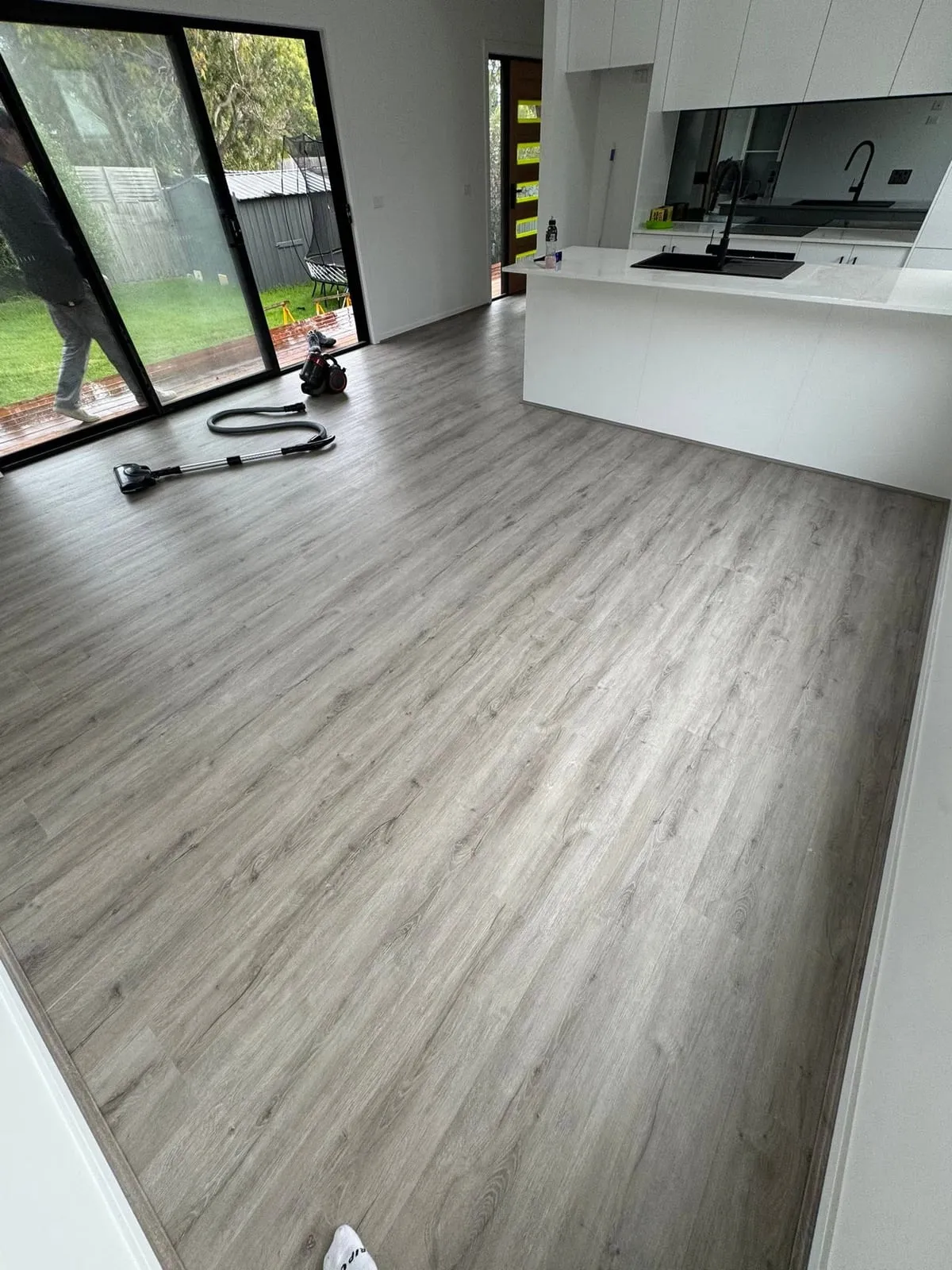 Grey timber-look hybrid flooring through an open kitchen and living area